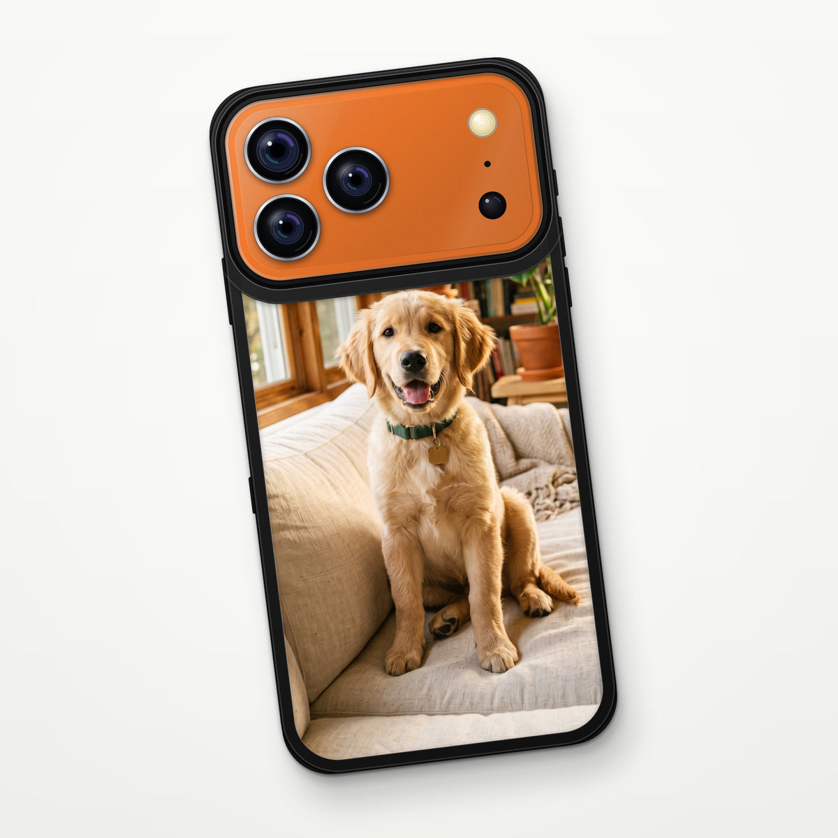 Kozmik turuncu iPhone 17 Pro Max üzerinde siyah çerçeveli MagSafe Frame Kılıf; şeffaf arka panele golden retriever yavrusu fotoğrafı basılmış, arkadan görünüm.